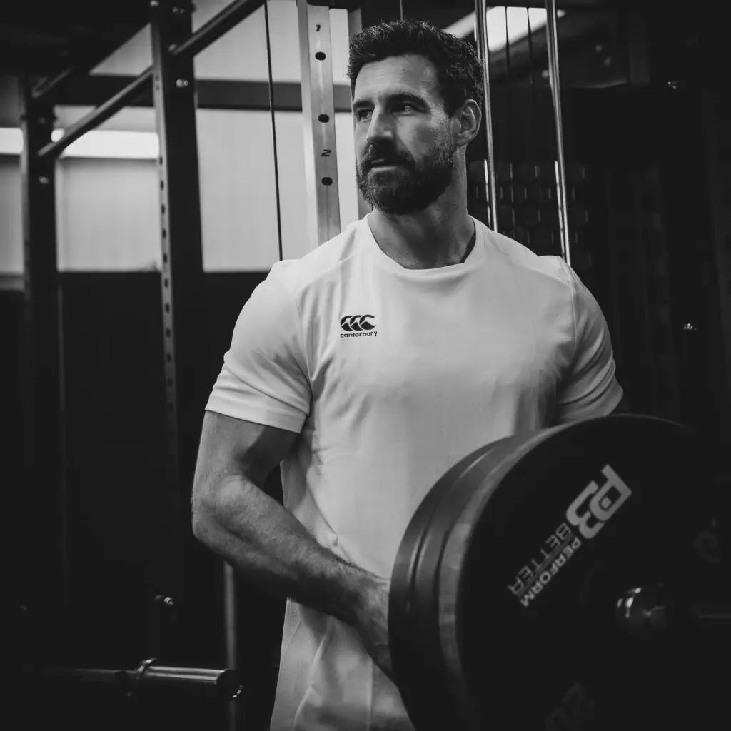 Man in gym stacking a barbell with weights.